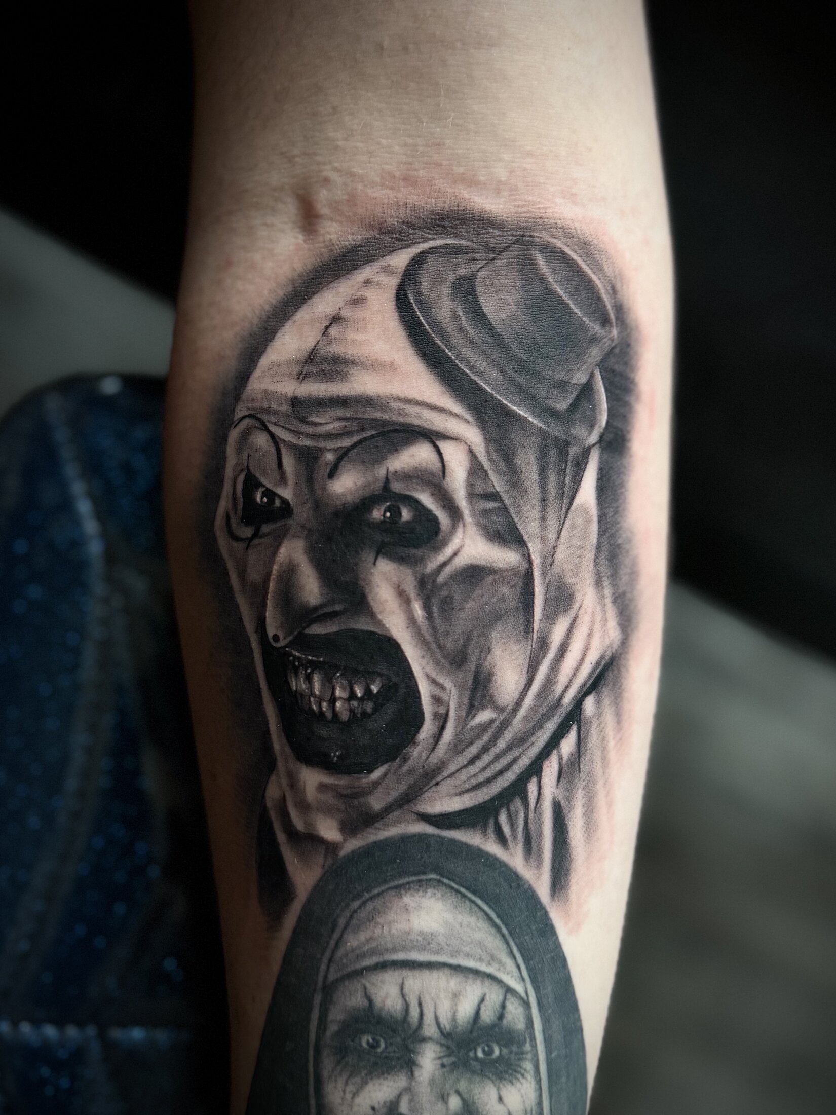 Black and grey realism horror clown portrait tattoo on a forearm