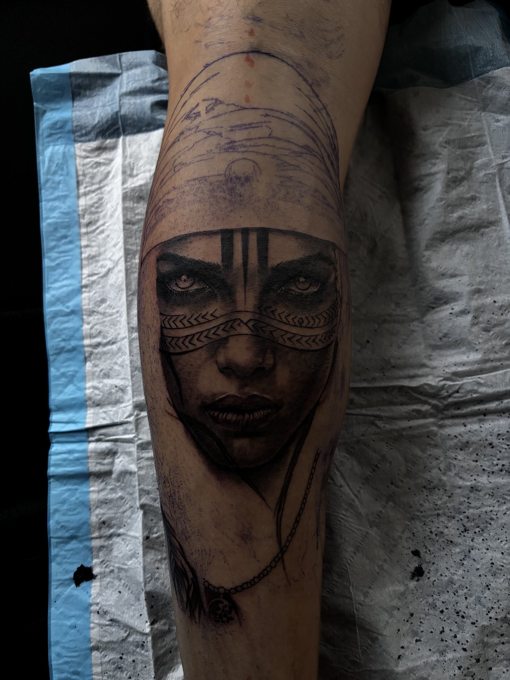 Black and grey realism portrait tattoo of a warrior woman with face paint on a calf